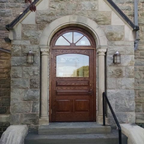Arched wooden entry door with glass panel by HS Windows.